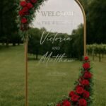 Gold Arch Wedding Welcome Sign with Red Rose Floral Arrangement